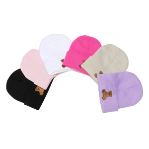 Detail view of multi-color knitted beanies with cute brown bear embroidery patches