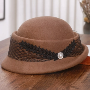 Détail du chapeau en laine marron avec dentelle noire, paillettes et une perle blanche