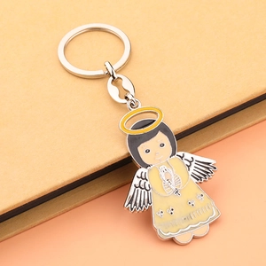 Portachiavi angelo in smalto cartone animato con vestito giallo su taccuino beige