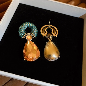 Detailed view of vintage drop earrings with teal rhinestones and orange faceted crystals