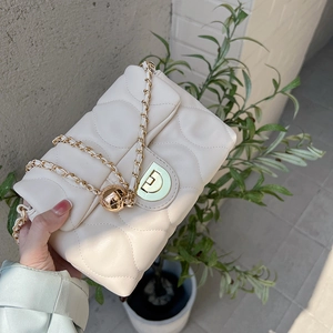 Detail shot of cream quilted crossbody bag with gold orb hardware and metal chain strap