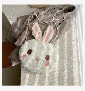 Detail of white plush bunny bag featuring soft faux fur and elegant pearl chain strap