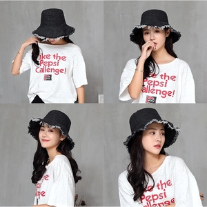 Détails d'un chapeau bob en denim noir présentant des bords effilochés et des finitions brutes