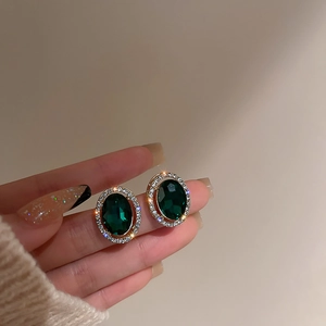 Dettaglio di orecchini vintage con smeraldo ovale e contorno di strass luccicanti