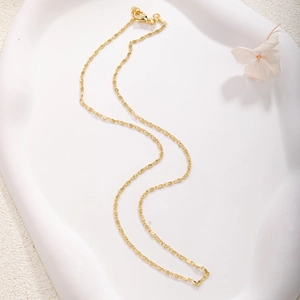 Detailed close-up of a gold-plated necklace with textured links and a lobster clasp