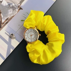 Detailed close-up of yellow scrunchie watch with gold case on dark background