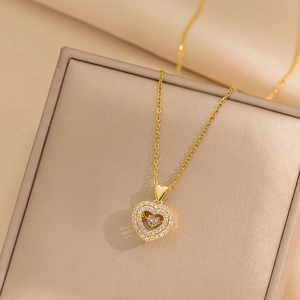 Elegant gold double heart pendant necklace with shimmering crystals on beige jewelry box
