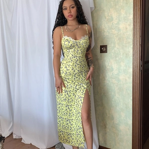 Detail of floral summer dress with lace neckline and high slit on yellow fabric