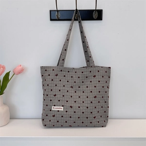 Détail du sac cabas en toile avec carreaux gris, pois rouges et broderie de nœud