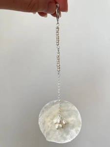 Detail of shell disk pendant earring with delicate small pearls on silver chain