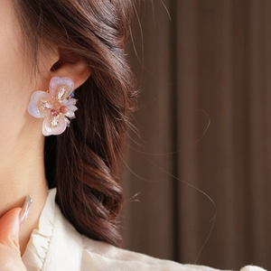 Gros plan sur les boucles d'oreilles fleur avec strass roses et perles sur l'oreille