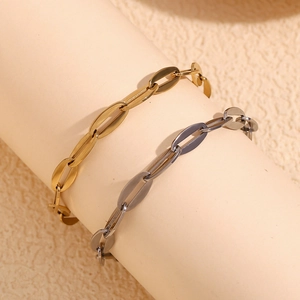 Gros plan de bracelets à maillons ovales dorés et noirs sur un support cylindrique