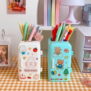Detail of creative refrigerator shaped pen holders with cute stickers on orange tablecloth