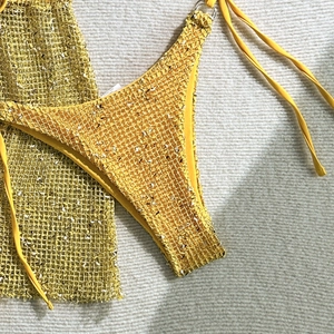 Detailed flat lay of mango yellow crochet bikini with metal ring and mesh beach cover-up
