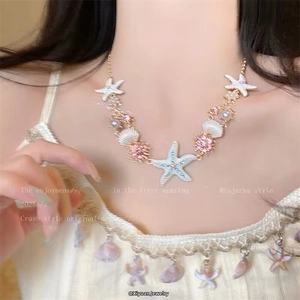Detail of beaded summer necklace with starfish shell charms and pink stone on a golden chain
