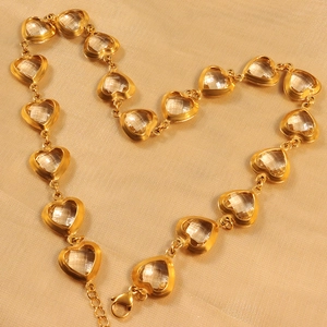 Minimalist gold heart-shaped zircon necklace set on gold silk fabric background