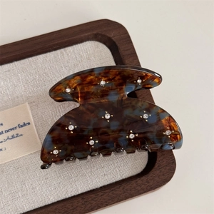 Detailed view of the tortoiseshell acetate hair claw clip with inlaid sparkling rhinestones
