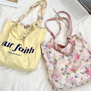 Detail of floral and graphic canvas tote bags with double-sided handles on white fabric