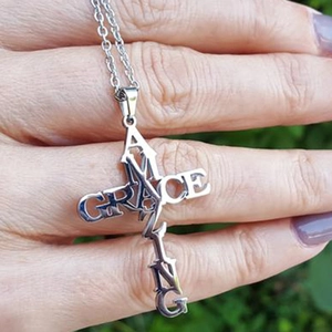 Silver stainless steel cross necklace with Amazing Grace cutout letters held by hand