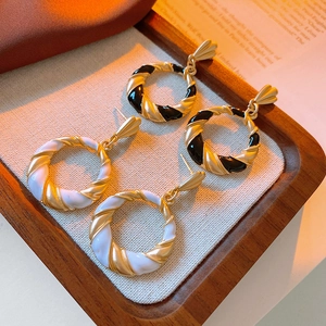 Detail of vintage twisted hoop earrings with black and white enamel finish on a tray