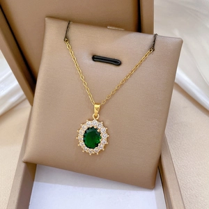 Macro detail of oval green emerald pendant with crystal halo on gold chain