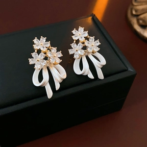 Gros plan sur les boucles d'oreilles nœud plaqué or avec fleur en zircon sur coffret