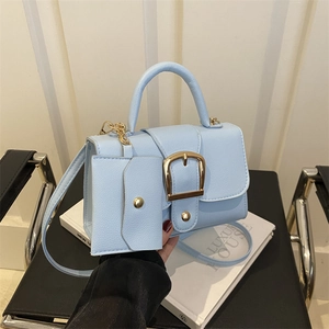 Minimalist light blue square handbag with matching card holder on a modern chair