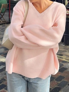 Close-up of pink V-neck knit sweater showing ribbed cuffs and loose fit style