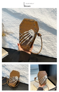 Detail of gothic coffin-shaped brown crossbody bag with skull embossing and bone hand