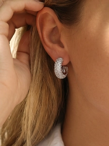 Close-up of silver C-shaped pavé hoop earrings with white zircon on a model ear