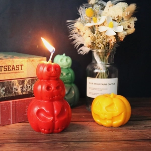 Halloween Jack-o'-lantern pumpkin candles in varied colors on a rustic wooden table