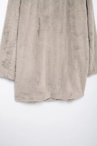 Close-up of soft light beige faux fur texture on the hem of a plush winter coat