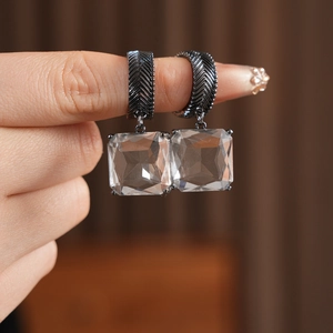 Détail de la boucle d'oreille en verre carré avec texture de plume gris foncé