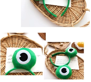 Détail d'un serre-tête en peluche verte avec de grands yeux sur fond tressé