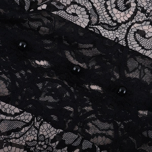 Detail of floral black lace fabric featuring elegant spherical beaded button closures