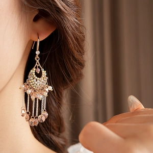 Detail of bohemian gold tassel earrings featuring pearls and multi-color crystals