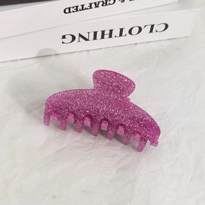 Close-up of a rose red glitter hair claw clip on a white textured fabric background