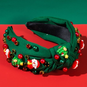 Dettaglio del cerchietto annodato verde con perle e ciondoli a forma di Babbo Natale