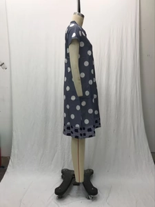 Detail of navy blue polka dot dress featuring geometric pattern hem trim on mannequin