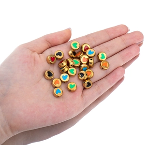Golden stainless steel heart beads for DIY jewelry making held in hand for scale