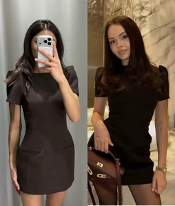 Detail view of a slim fit black mini dress featuring puff sleeves and square neckline