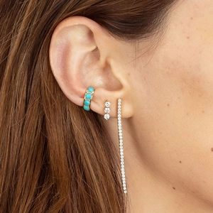 Close-up of gold ear climber set with turquoise and crystal studs on a woman's ear