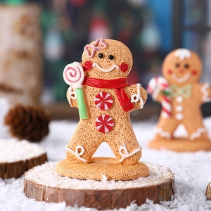 Charming resin gingerbread man ornament with red scarf on snowy wooden base display