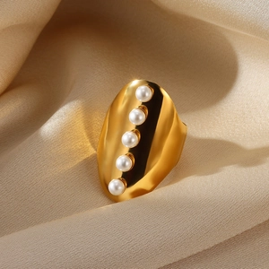 Macro shot of 5 white pearls on a gold oval ring over beige silk fabric background