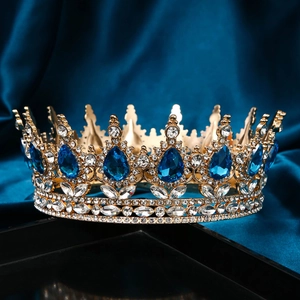 Close-up of golden crown featuring blue teardrop gemstones and sparkling clear crystals