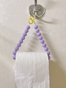 Detail of purple beaded toilet paper holder with yellow ring and metal wall hook