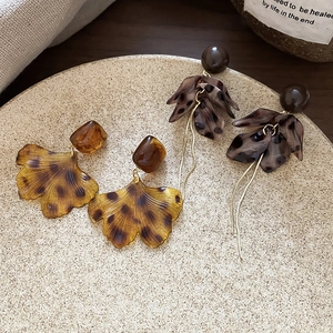 Gros plan de boucles d'oreilles feuille de ginkgo en résine ambrée dans un plat céramique