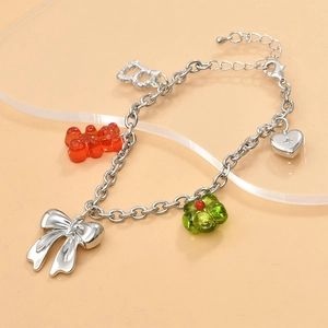 Detail of silver Y2K charm bracelet featuring a red gummy bear and metallic bow charms