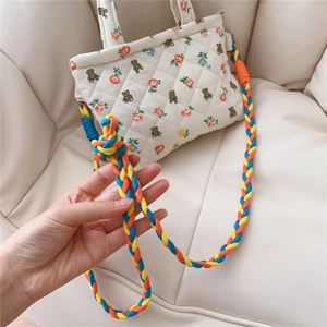 Detail of quilted floral mini crossbody bag with a colorful braided rope shoulder strap