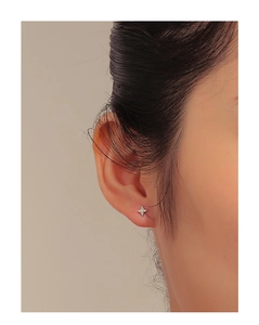 Detail of S925 silver star stud earring with zircons worn on earlobe for daily look